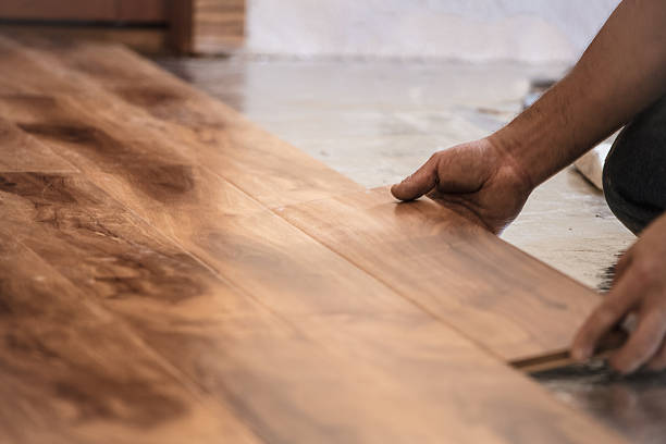 Man installing wood flooring in home.